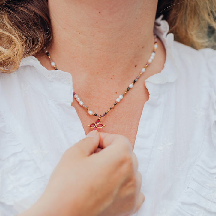 Jeune femme portant un Collier Murmures Precieux® Bijoux créé avec l'alphabet Morse Mère veilleuse en pierre aventurine, perles de culture, enfilé à la main avec un pendentif en croix