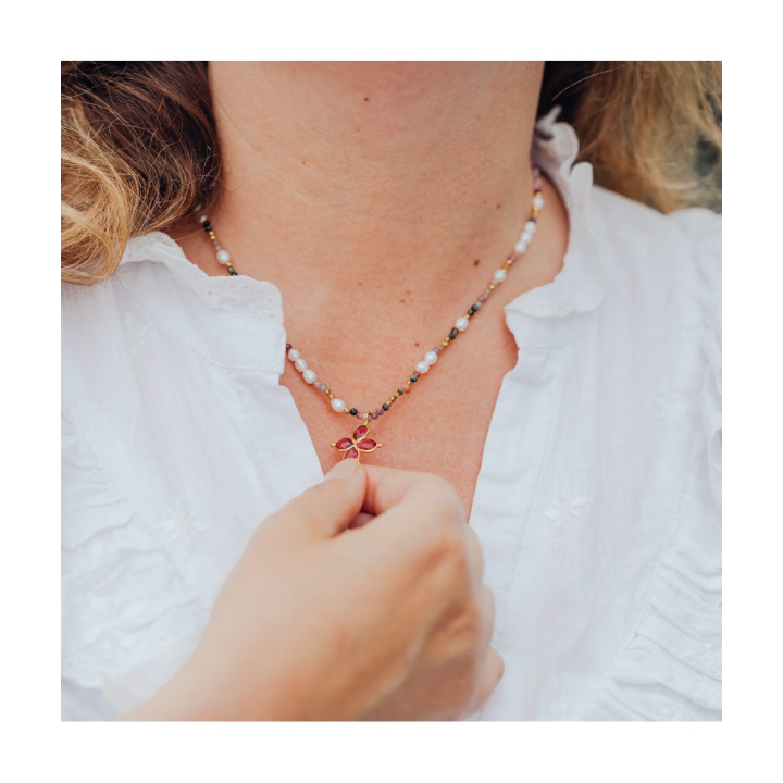Young women wearing Murmures Precieux® dash and dot jewellery ‘Mère veilleuse’ necklace in aventurine semi-precious stone and cultured pearls, hand-thread, with a cross pendant on its pink velvet packaging with jewellery purse