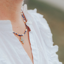 Young women wearing a Murmures Precieux® dash and dot jewellery murmures secret necklace in lapis-lazuli semi-precious stone and cultured pearls, hand-thread, with a light blue cross pendant