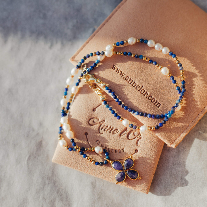 Murmures Precieux® dash and dot jewellery murmures secret necklace in lapis-lazuli semi-precious stone and cultured pearls, hand-thread, with a lapis-lazuli cross pendant on its pink velvet packaging with jewellery purse