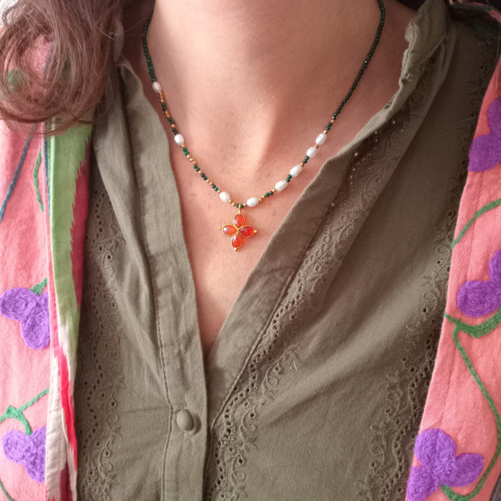 Jeune femme portant un collier Murmures Precieux® Bijoux créé avec l'alphabet Morse à murmures secrets en pierre fine spinelle noir, perles de culture, enfilé à la main avec un pendentif en croix orangec