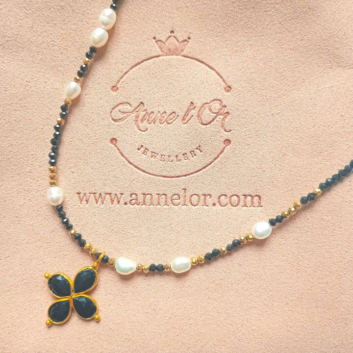 Murmures Precieux® dash and dot jewellery ‘Mère veilleuse’ necklace in black spinel semi-precious stone and cultured pearls, hand-thread, with a cross pendant on its pink velvet packaging with jewellery purse